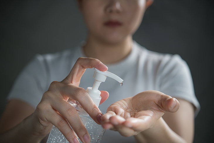 Mulher aplicando álcool gel nas mãos. Biossegurança contra coronavírus.