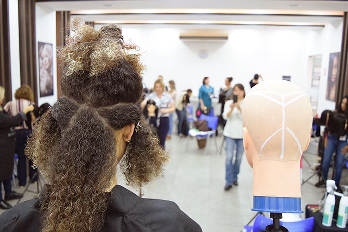 Mulher com corte de cabelo cacheado curto com luzes.