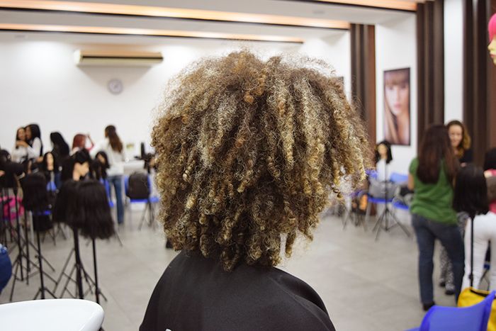 Mulher com corte de cabelo cacheado curto com luzes.