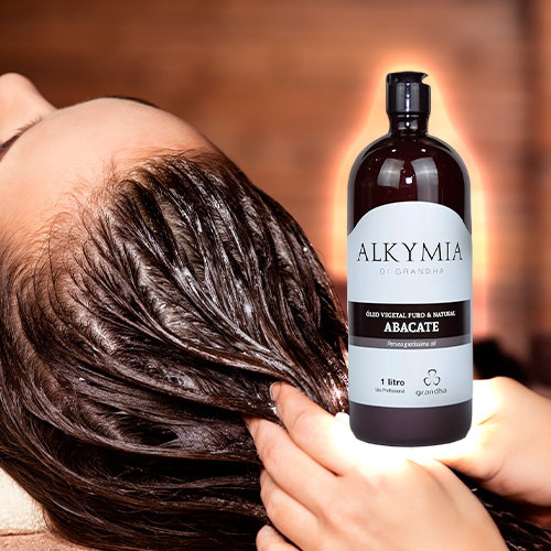 Mulher recebe tratamento capilar com óleo de abacate Alkymia da Grandha; foco no brilho e nutrição dos fios.