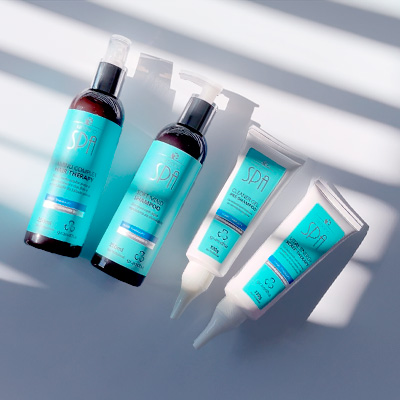 Kit de cuidados capilares Urbano Spa Blue da Grandha, com cinco produtos em embalagens azul-turquesa, sob luz suave com sombras de persianas.