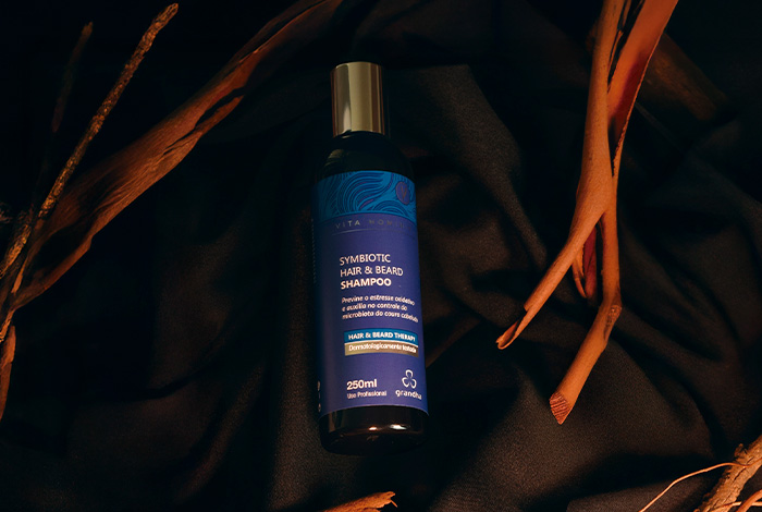 Shampoo para barba e cabelo: mais praticidade para o homem moderno 1 Imagem de um shampoo masculino para cabelo e barba em embalagem preta, fotografado sobre fundo escuro com detalhes de madeira ao redor.