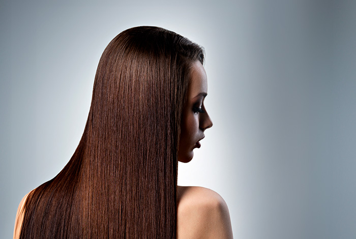 Mulher de perfil com cabelos longos, lisos e brilhantes, destacando a textura uniforme e o aspecto saudável dos fios.