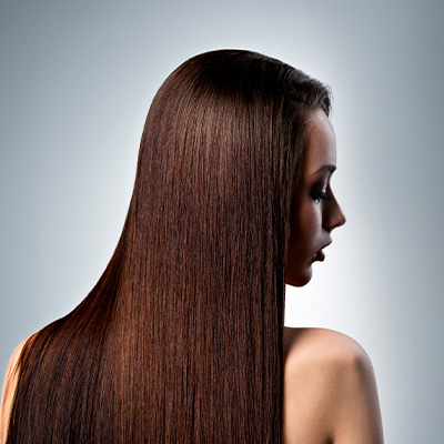 Mulher de perfil com cabelos longos, lisos e brilhantes, destacando a textura uniforme e o aspecto saudável dos fios.