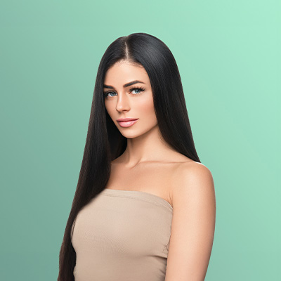 Mulher com cabelos longos, lisos e brilhantes posa de frente em fundo verde, destacando aparência saudável dos fios.