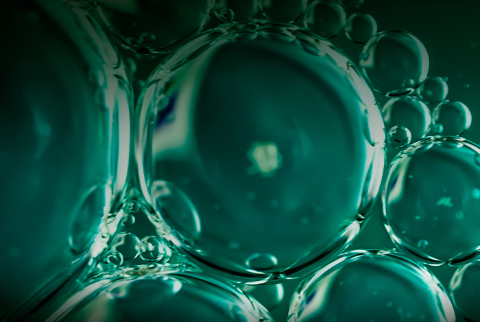 Macro de bolhas translúcidas em líquido, formando textura fluida que remete a processos químicos ou biotecnológicos.