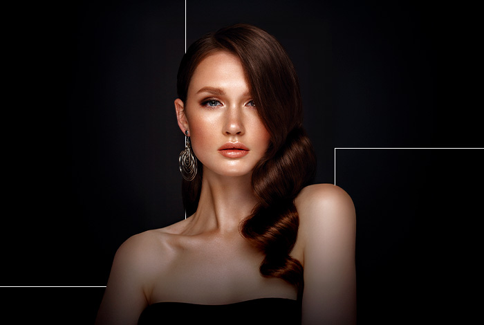 Retrato de mulher com cabelo estilizado e maquiagem sofisticada, em fundo escuro com estética elegante e moderna.