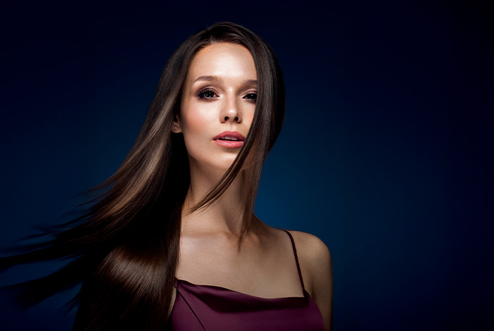 Mulher com cabelos longos, lisos e brilhantes em destaque, representando beleza, saúde capilar e cuidados cosméticos.