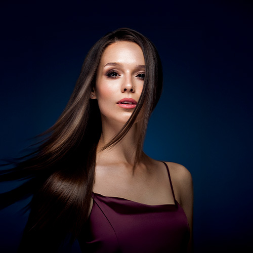 Mulher com cabelos longos, lisos e brilhantes em destaque, representando beleza, saúde capilar e cuidados cosméticos.