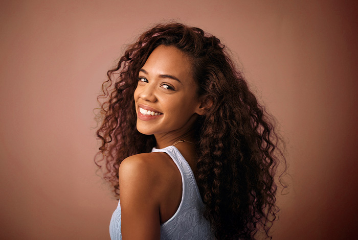 Mulher sorridente com cabelos cacheados volumosos e definidos.