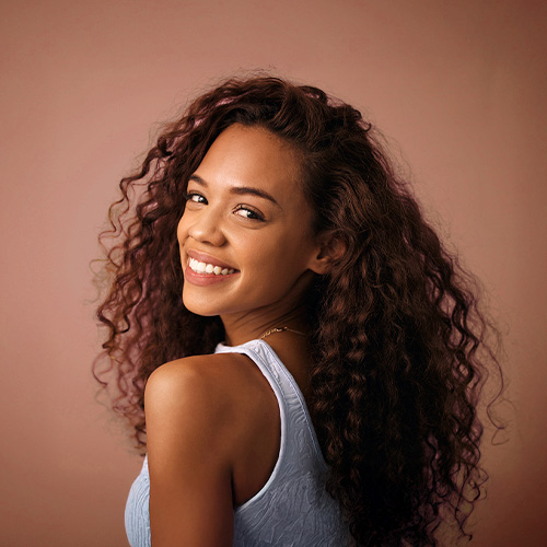Mulher sorridente com cabelos cacheados volumosos e definidos.
