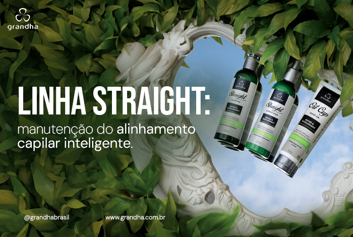 Linha Straight: manutenção do alinhamento capilar inteligente. 1 Frascos e bisnaga da linha Straight Grandha suspensos diante de um espelho com moldura ornamentada, cercados por folhagens, com fundo de céu azul.