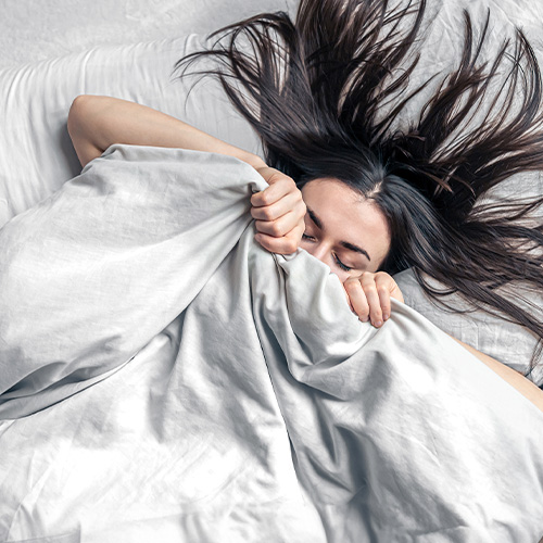 Mulher deitada na cama com cabelo sobre o travesseiro