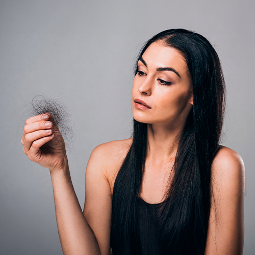 Mulher observando fios de cabelo soltos na mão