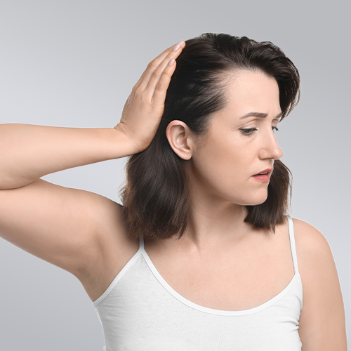 Mulher observando o cabelo em conteúdo sobre alopecia androgenética