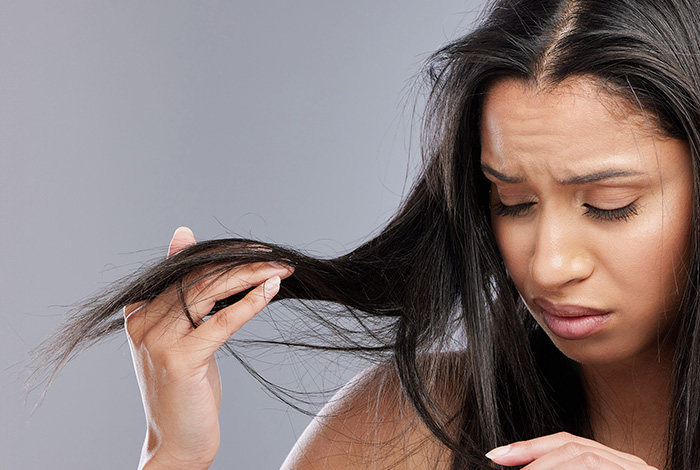 Mulher analisando pontas de cabelo ressecado e com frizz